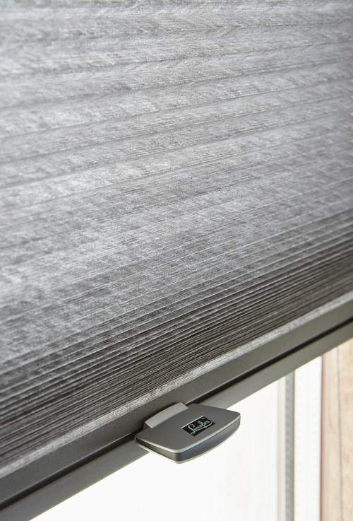 Grijze duette shades met handgreepbediening met Luxaflex logo erop